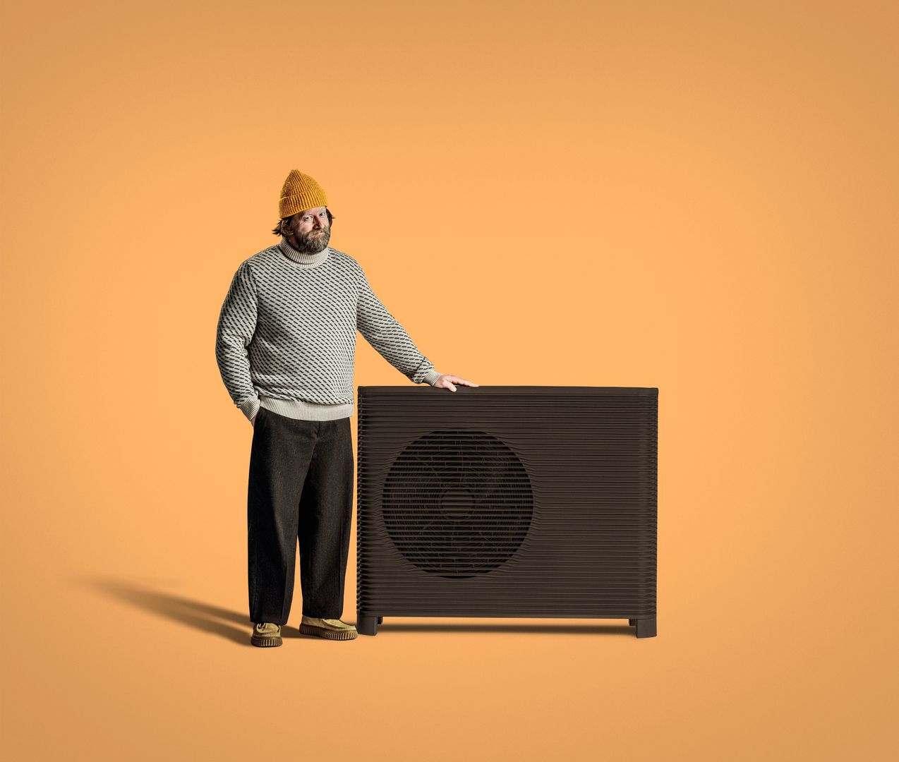 Swedish man named Eric standing by Aira Heat Pump in front of orange background