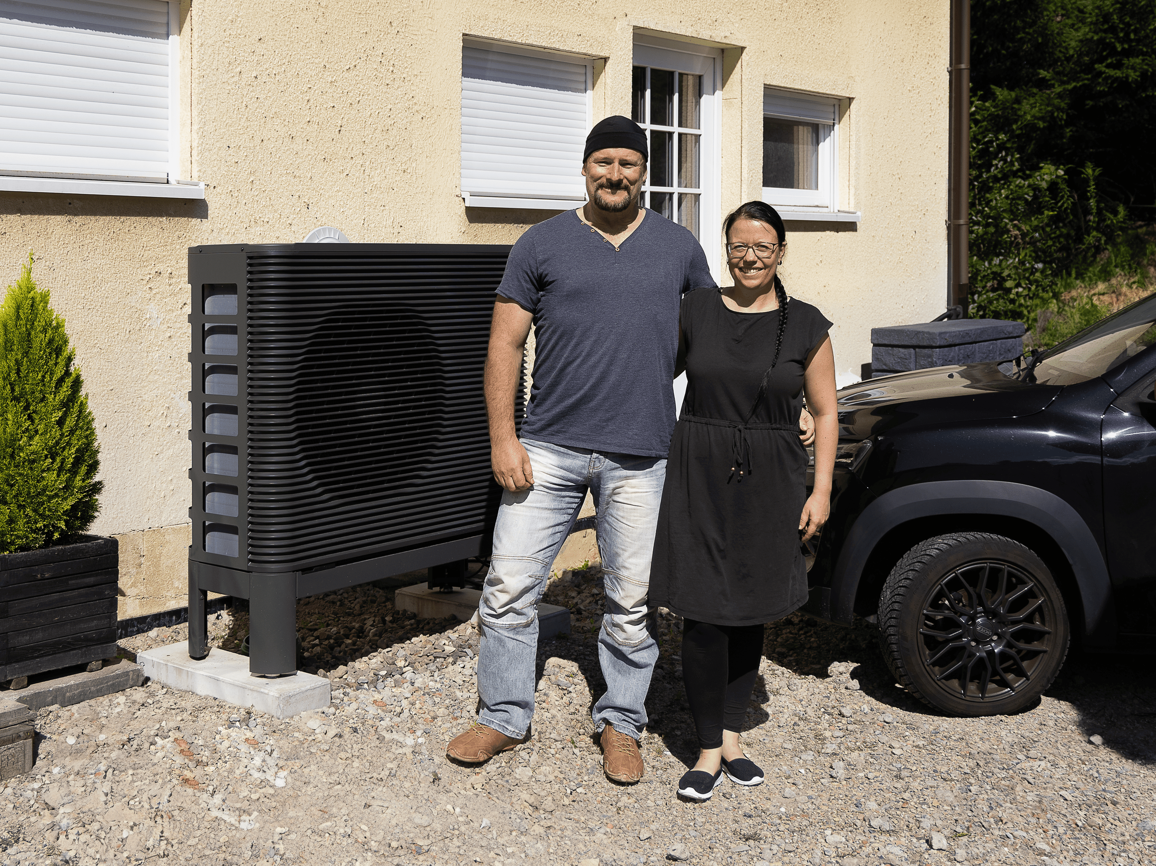 Ein Pärchen steht vor ihrem Haus vor der neuen Wärmepumpe