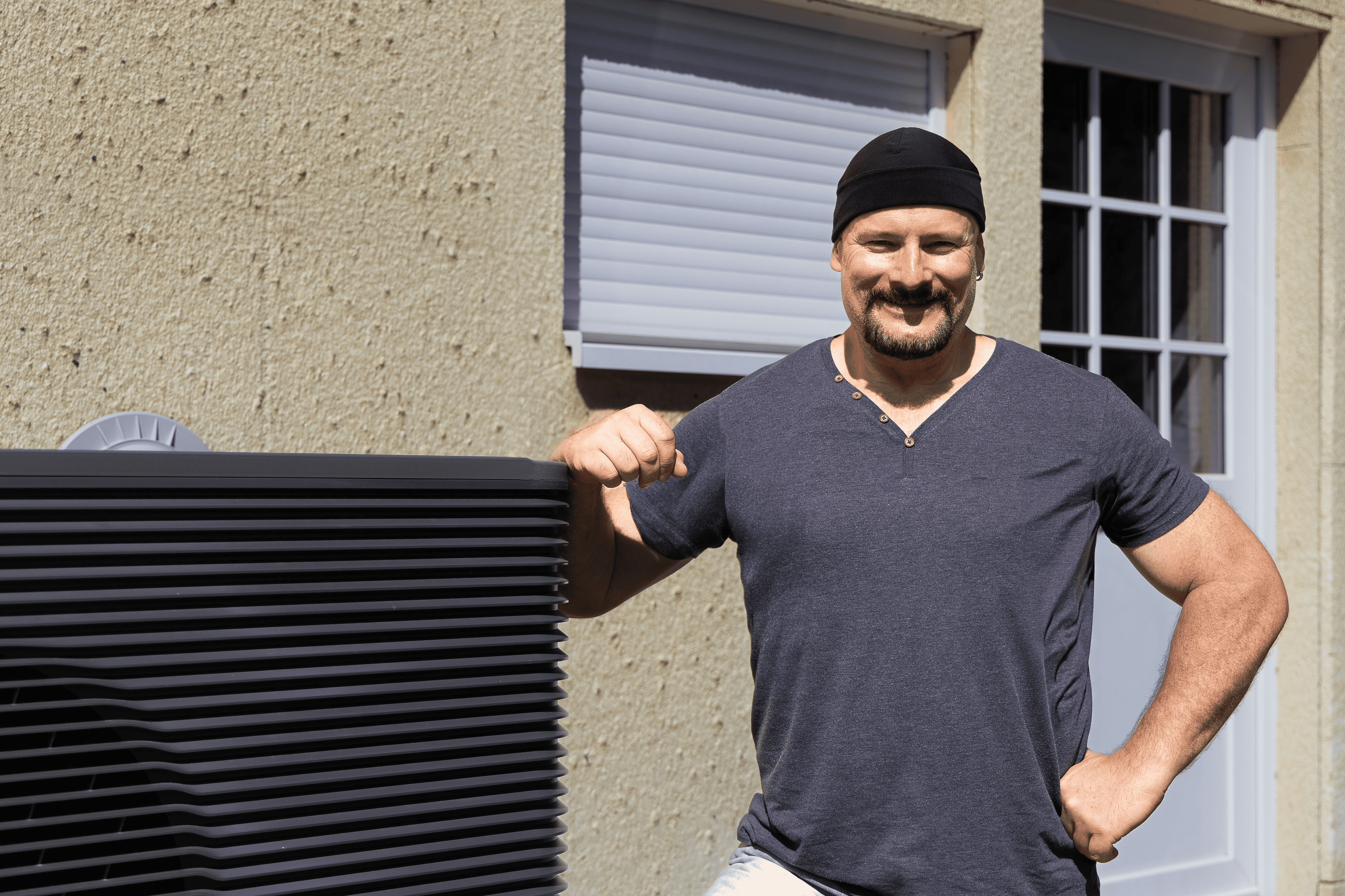 Ein Mann steht vor seinem Haus vor der neuen Wärmepumpe