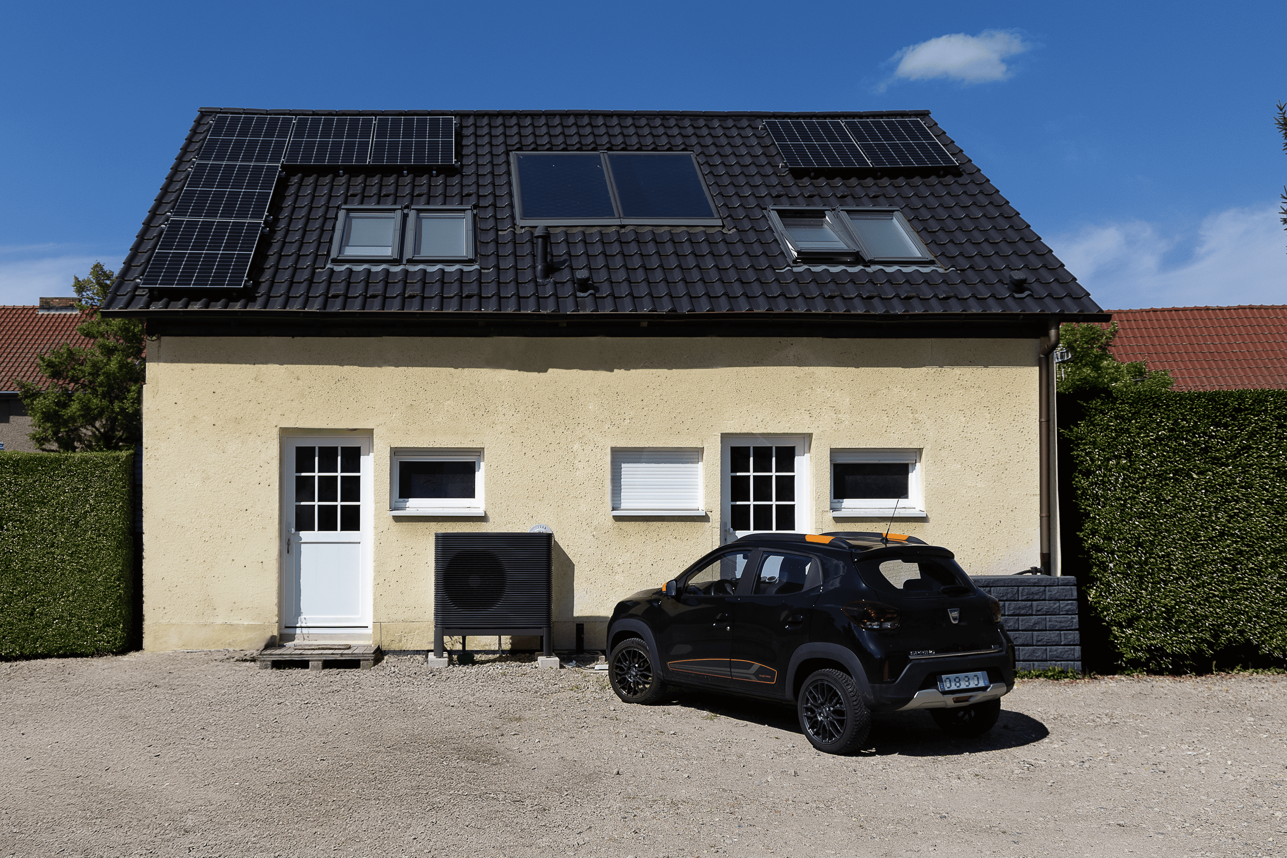 Einfamilienhaus mit einer Wärmepumpe, PV-Anlage auf dem Dach, und ein Elektroauto