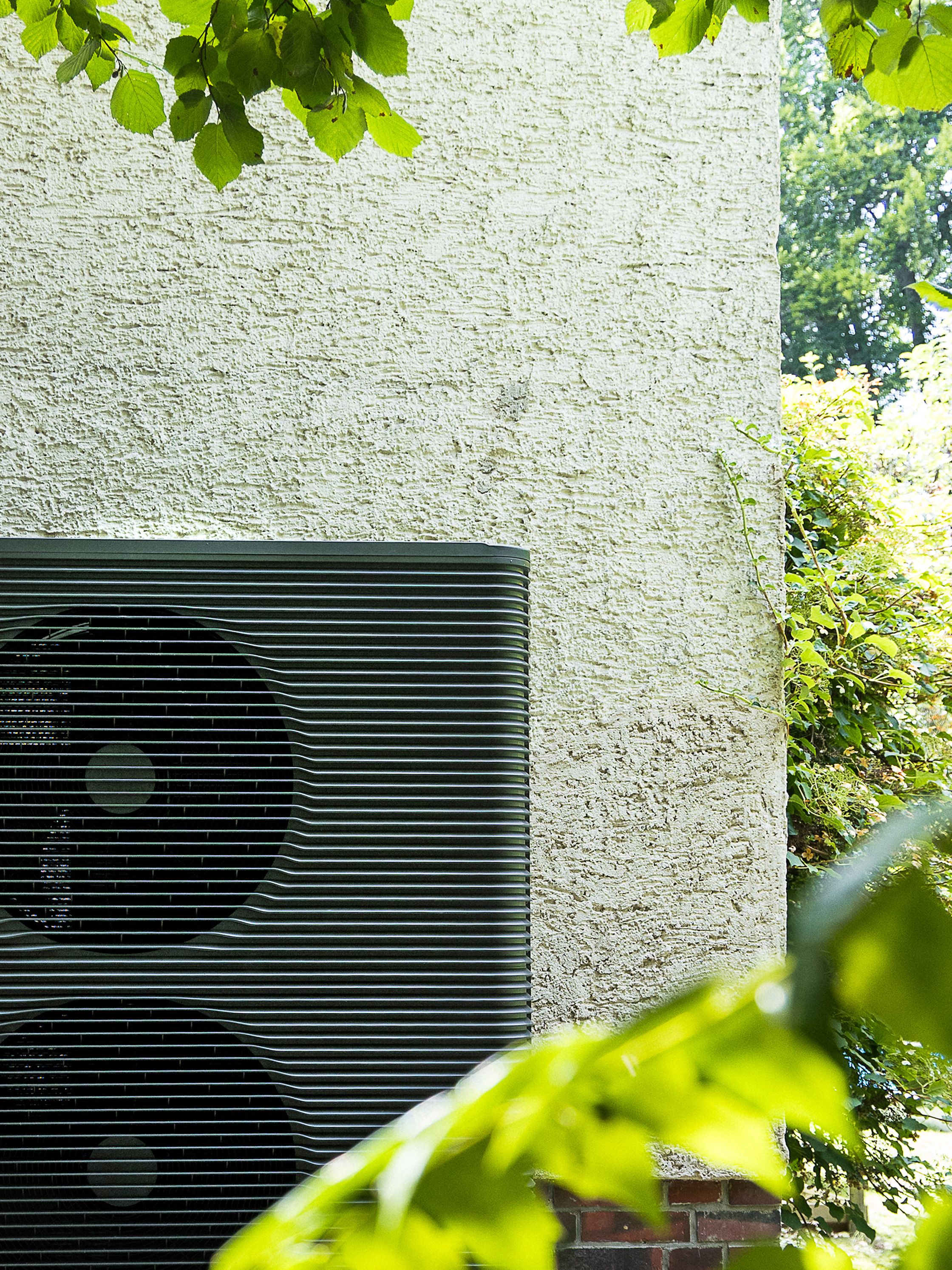 Eine Wärmepumpe vor einer weißen Häuserwand