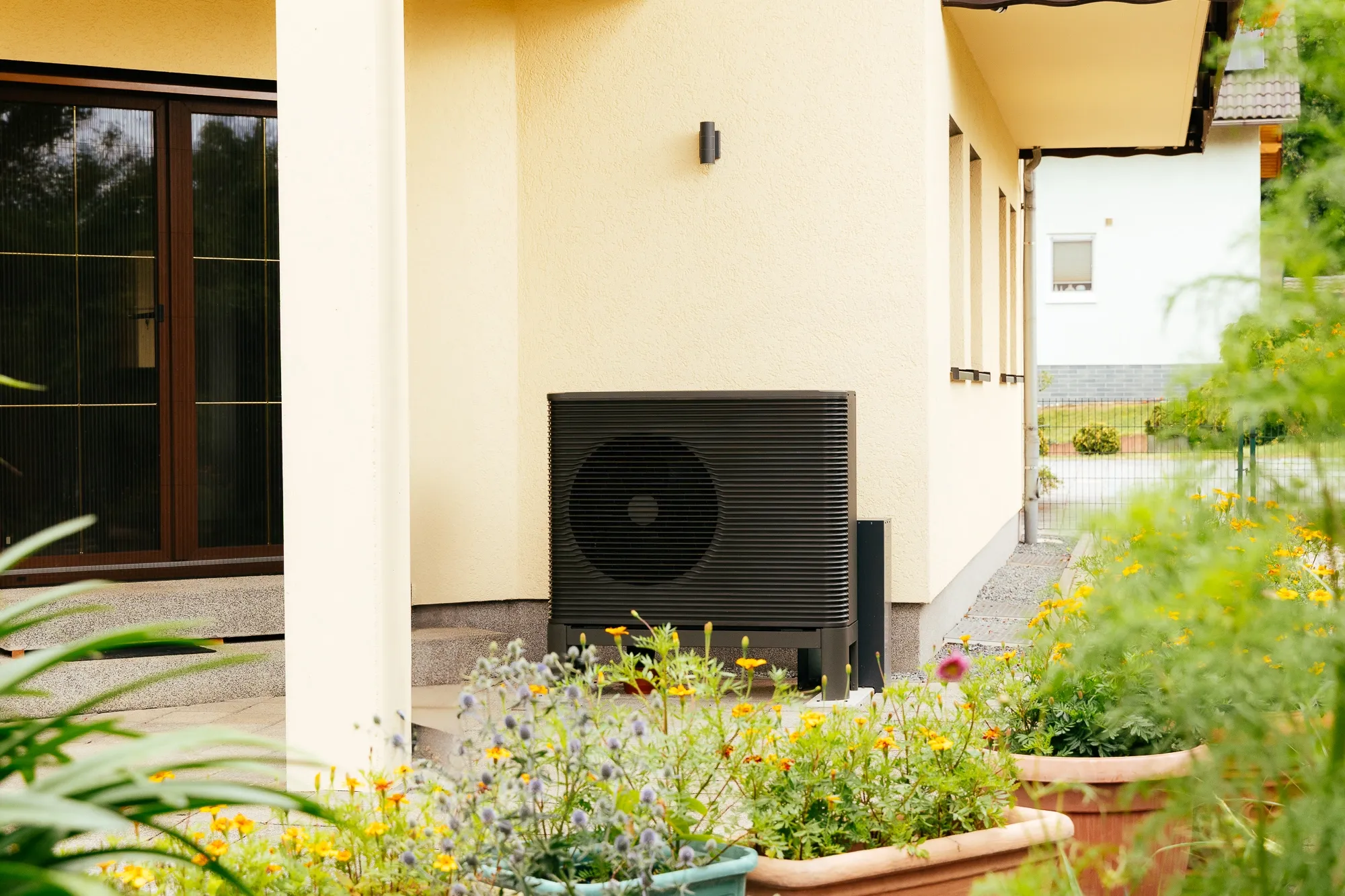 Zu sehen ist eine Wärmepumpe an einer Hauswand an einem Altbau, Einfamilienhaus