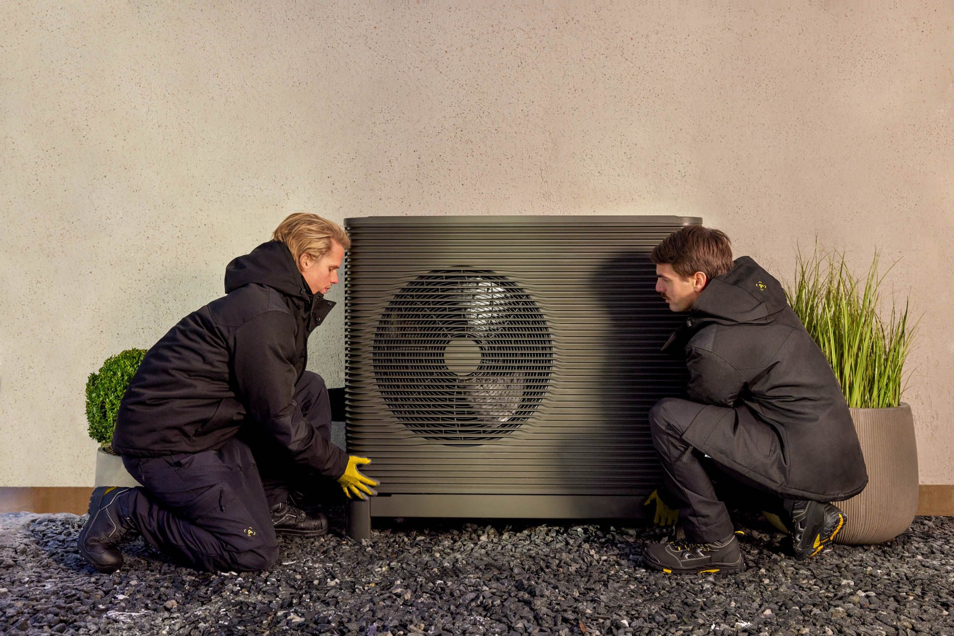 zwei Mitarbeiter von Aira installieren eine Luft-Wasser-Wärmepumpe