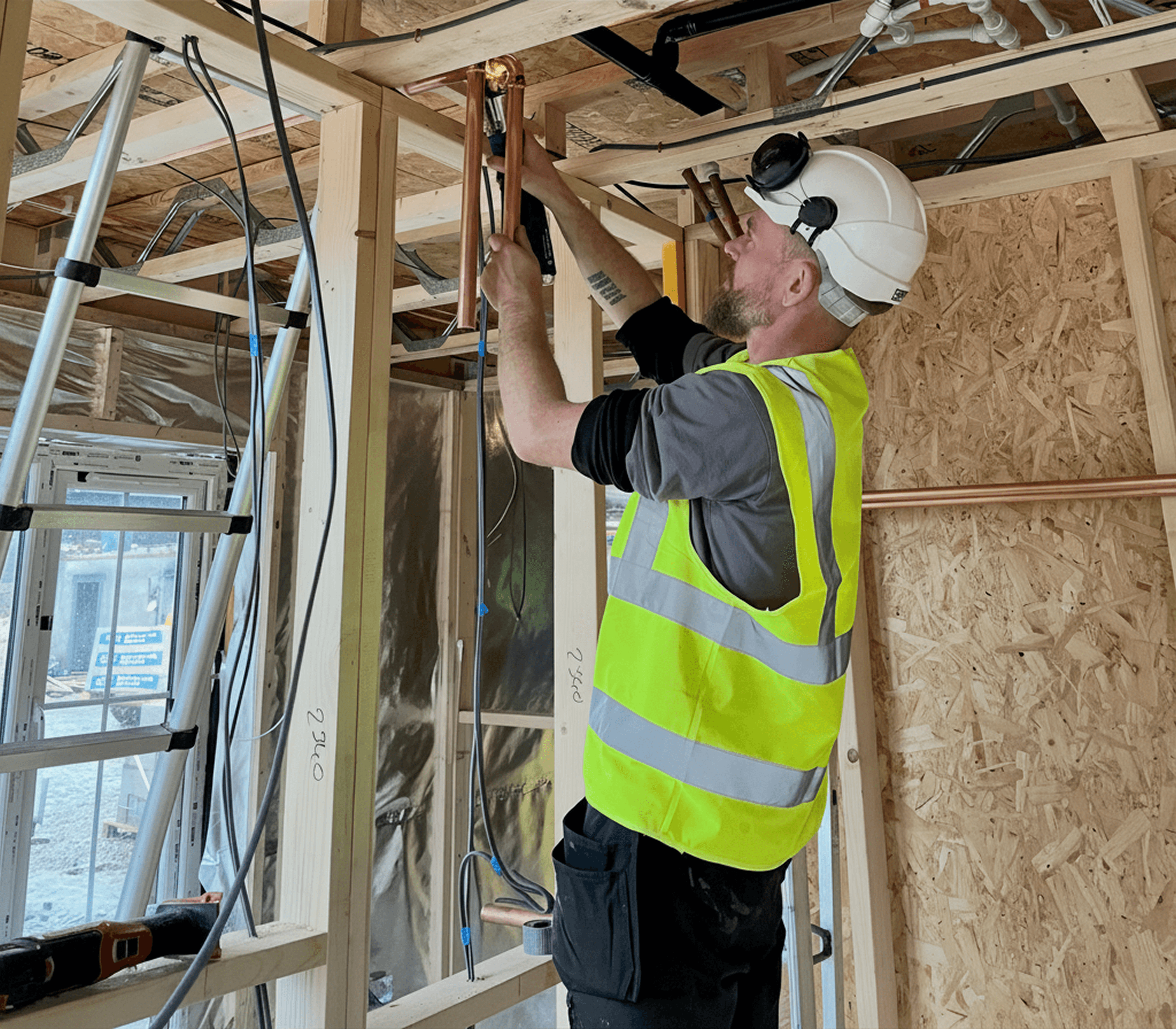 Aira installer working on piping for an Aira Heat Pump at a building development