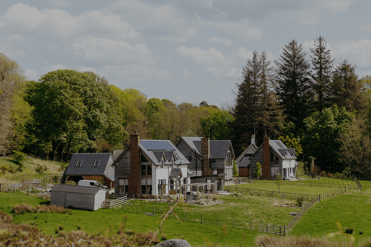 Picture of a house in the countryside with solar panels and Aira Heat Pump