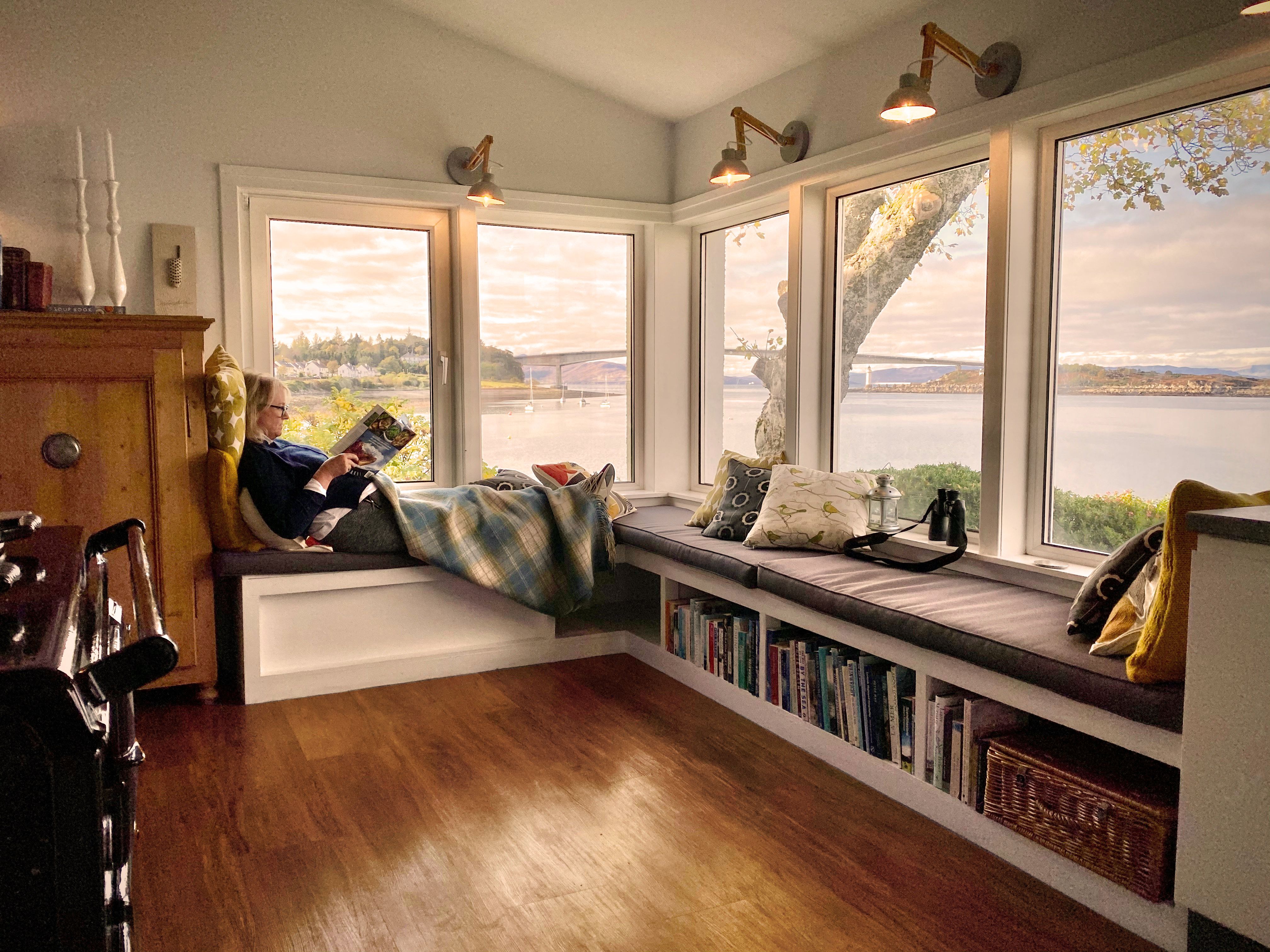 Woman sitting at her window in her home in Scotland reading a magazine