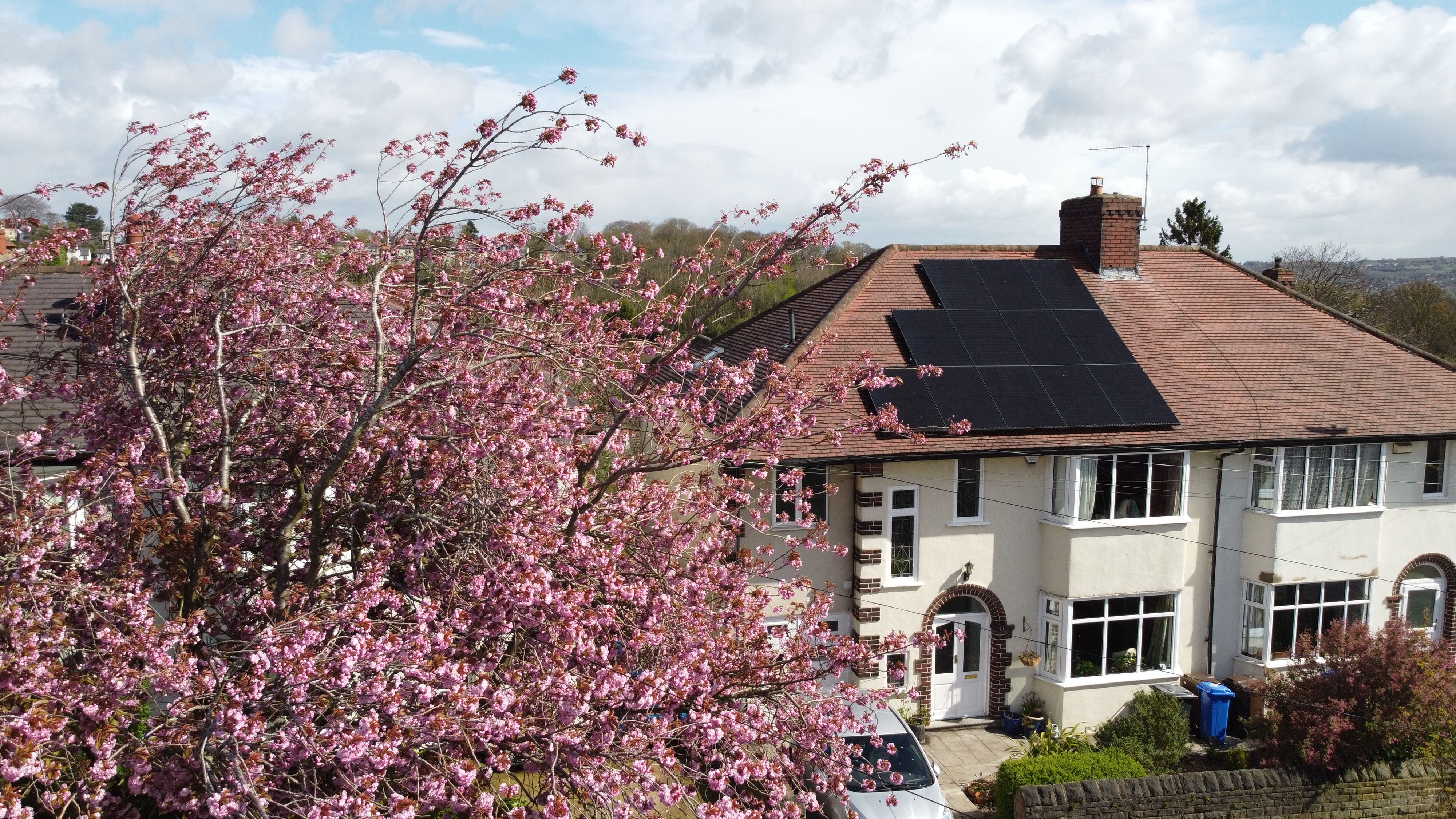 Solar panels on UK semi-detached home with a tree in front of the home