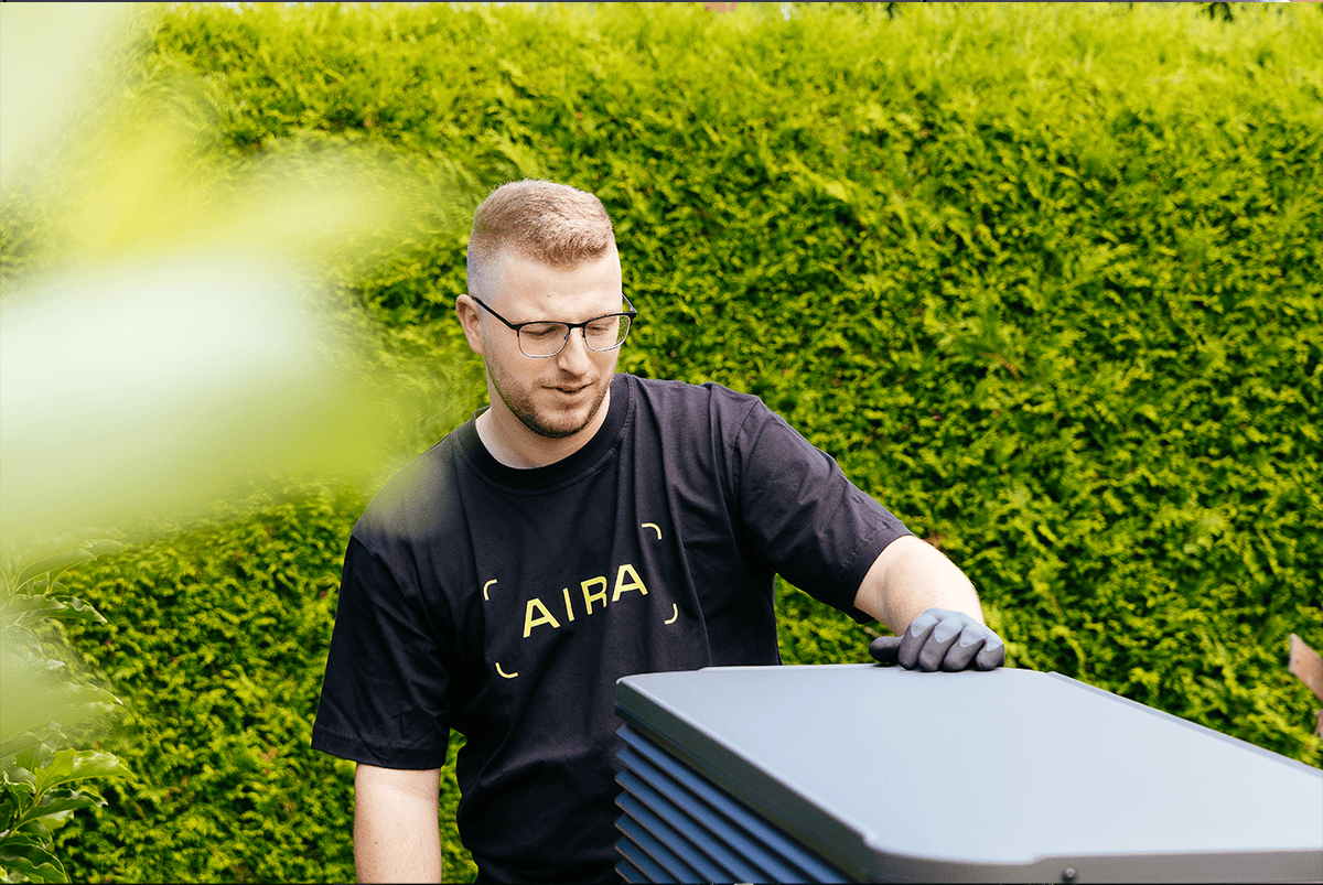 Zu sehen ist ein Installateur der gerade eine Wärmepumpe ausrichtet