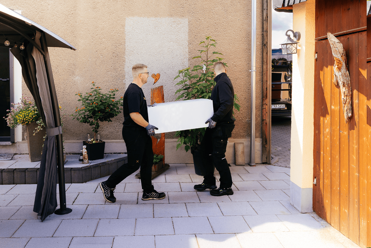 Zwei Monteure tragen eine alte Gasheizung